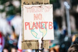 A hand holds a hand-drawn sign that reads "There is no planet B"
