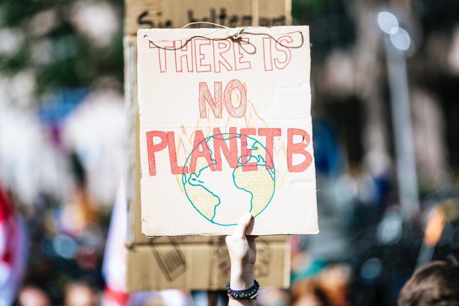 A hand holds a hand-drawn sign that reads 
