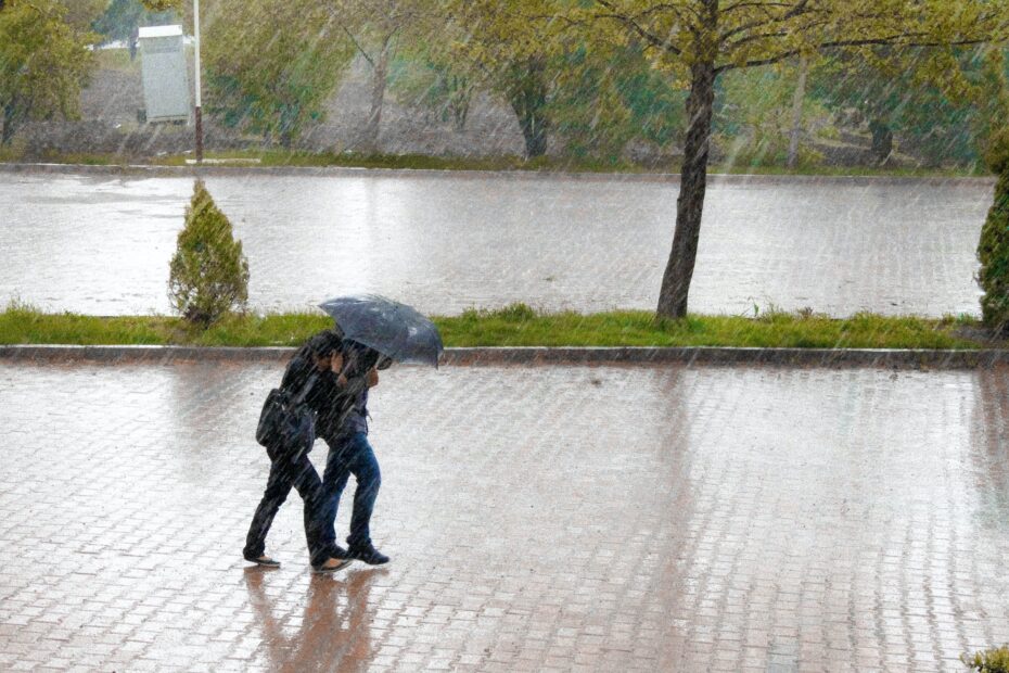 Two people walking with an umbrella in heavy rain