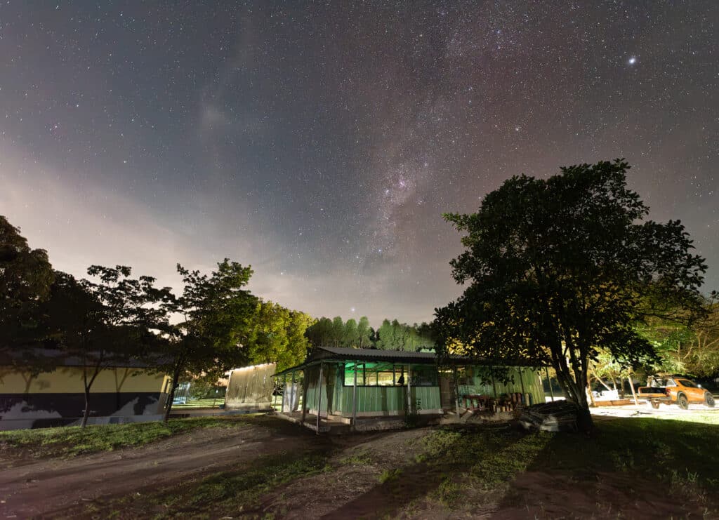 night sky with stars and milky way over green shed and buildings of research station