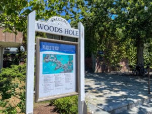 a wooden sign that reads "welcome to woods hole" above a map