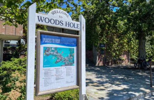 a wooden sign that reads "welcome to woods hole" above a map