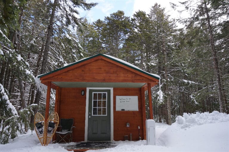 a red wooden building at the research station sits in snowy forest