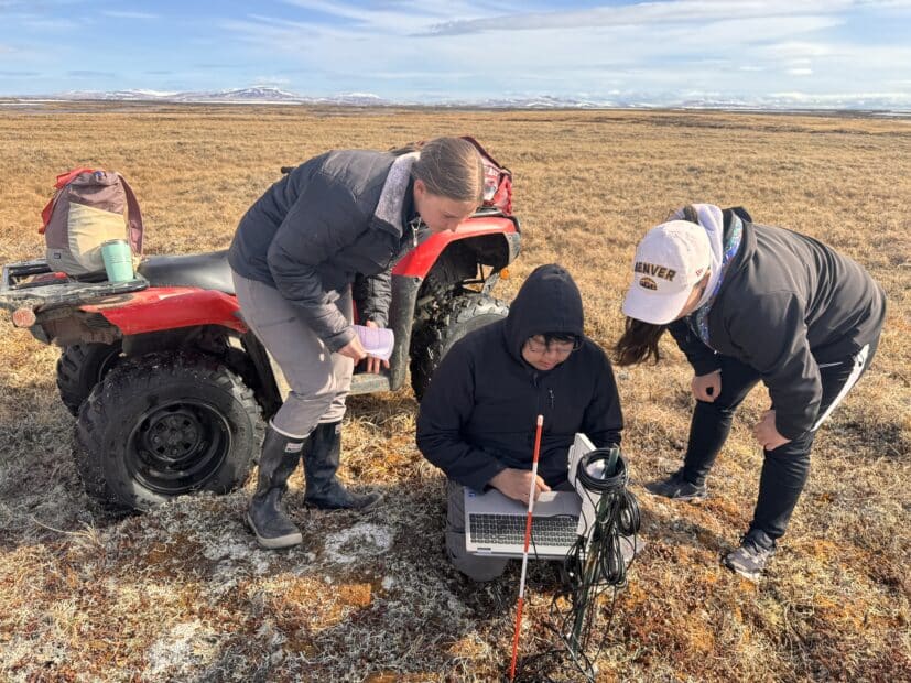 Tiffany Windholz, Reggie Tuluk, Permafrost Pathways Tribal Liaison for the Native Village of Cev’aq, and Darcy Peter downloading data from a temperature sensor.
