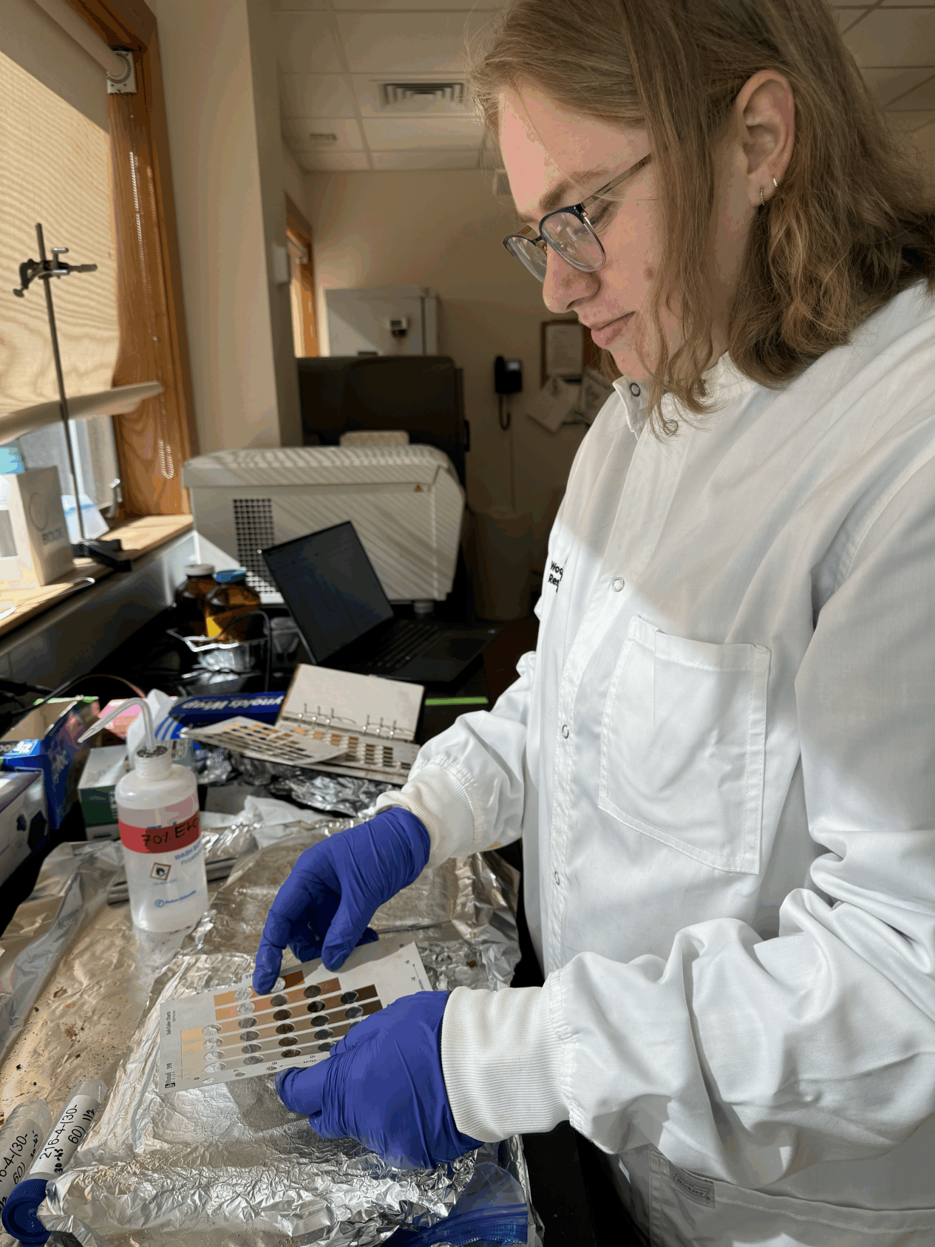 Marly Bartkus in a lab coat and gloves prepares samples at a lab bench