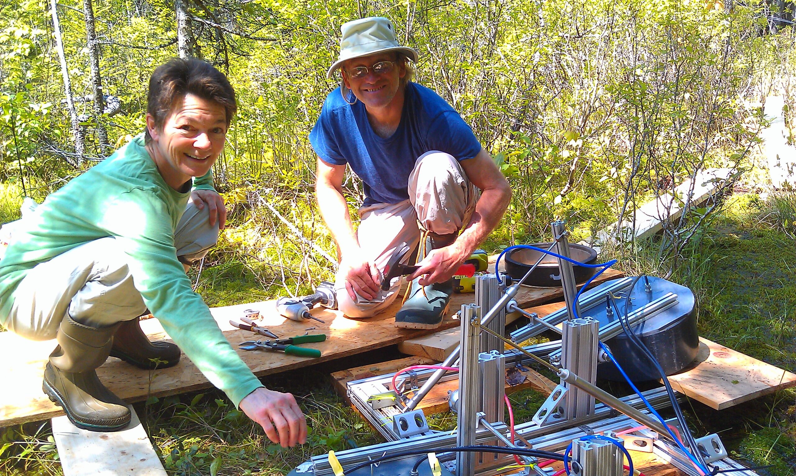 Two researchers installing an automated greenhouse gas flux chambers in the wetlands at Howland