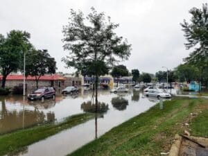 cars in the flooded parking lot of a strip mall, with water reaching about halfway up their tires