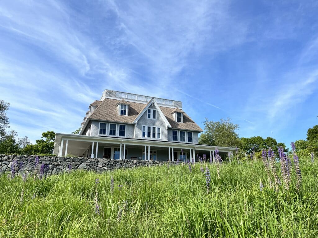 the woodwell climate campus building stands in a field of grass with a blue sky behind it