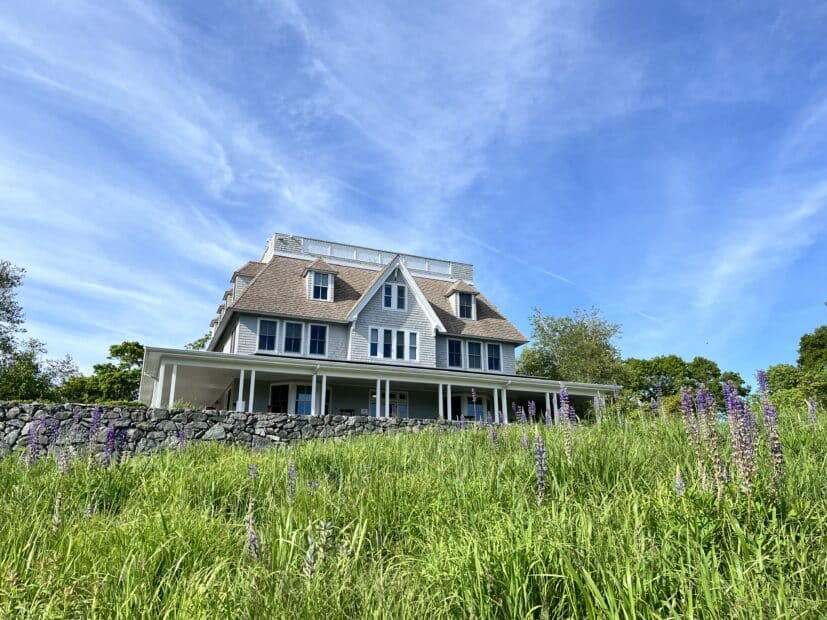 the woodwell climate campus building stands in a field of grass with a blue sky behind it