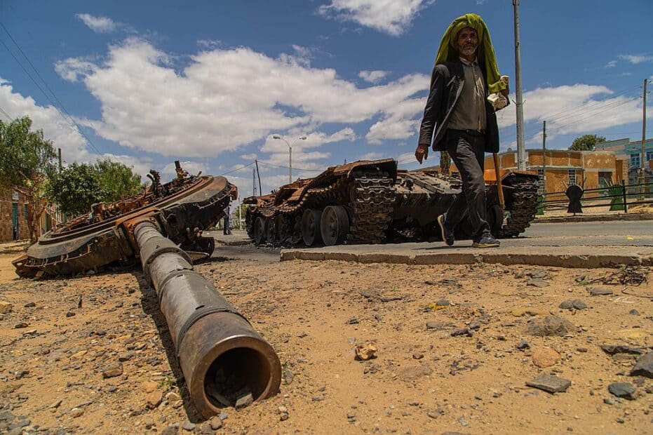 a man passes by a destroyed tank in the street