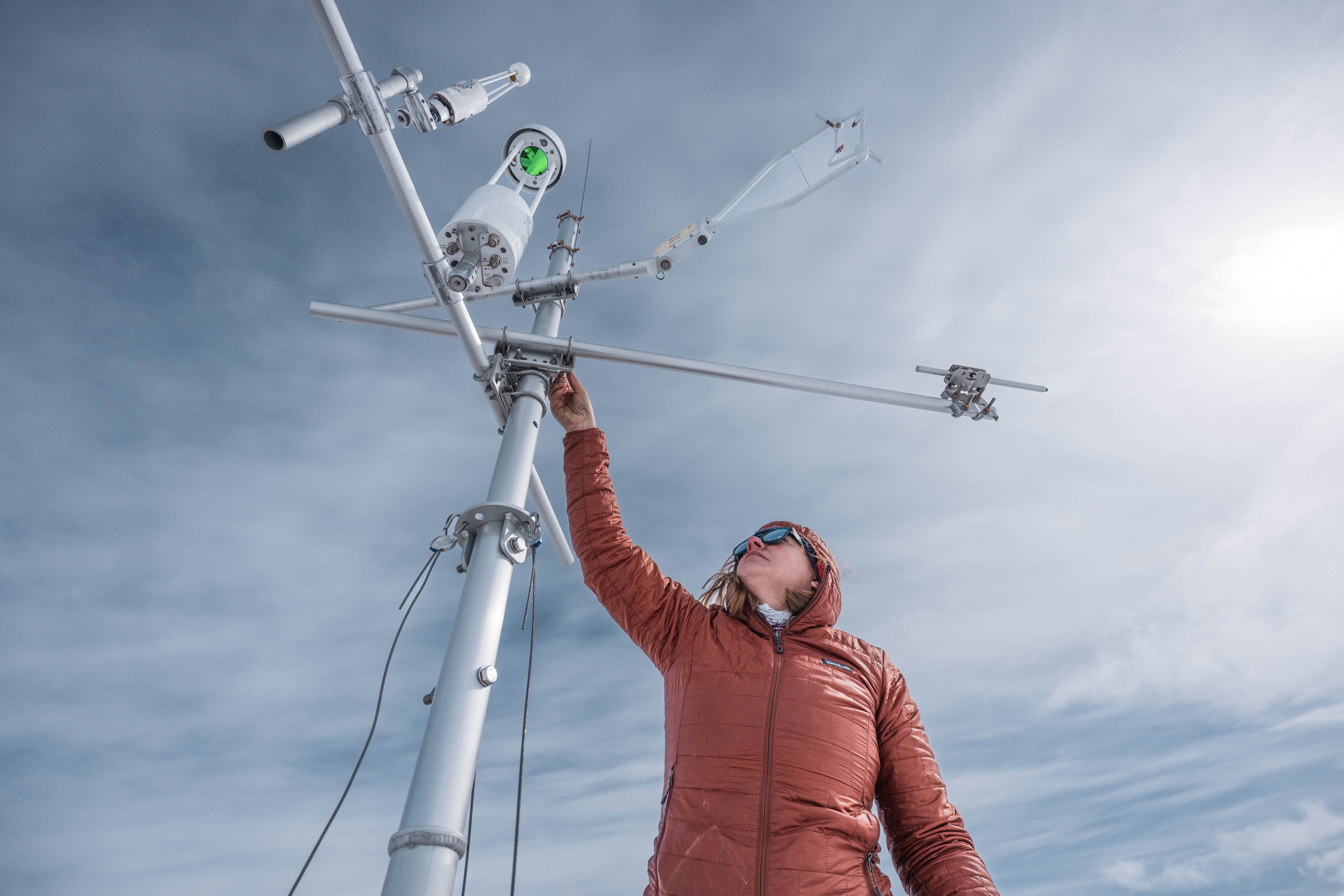 jenny watts reaches up to a carbon tower to adjust a piece of equipment