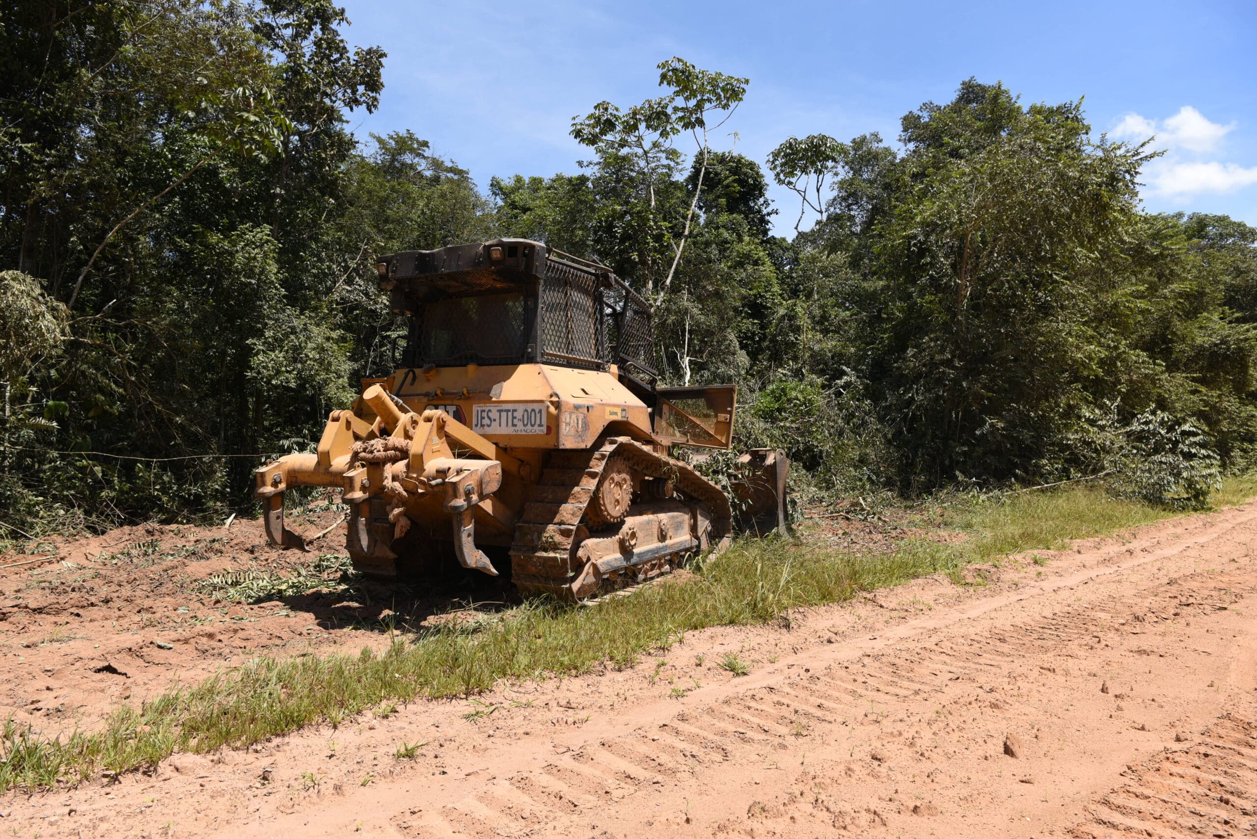 a bulldozer widens a road on an Amazonian farm