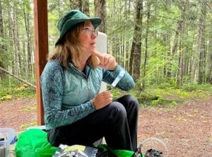 kathleen savage sits in a forest holding a syringe containing a water sample