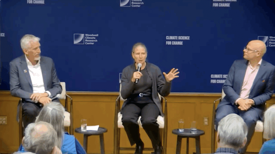 Max Holmes, Frances Seymour, and Matti Goldberg sit in chairs while Frances speaks into a microphone