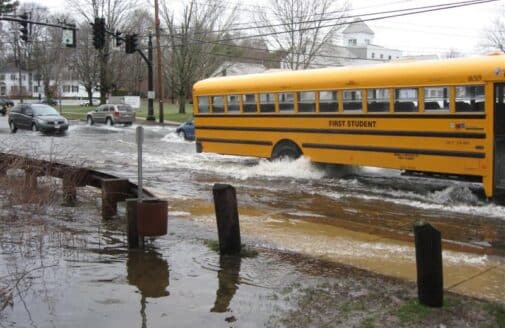 a school bus drives on a flooded road