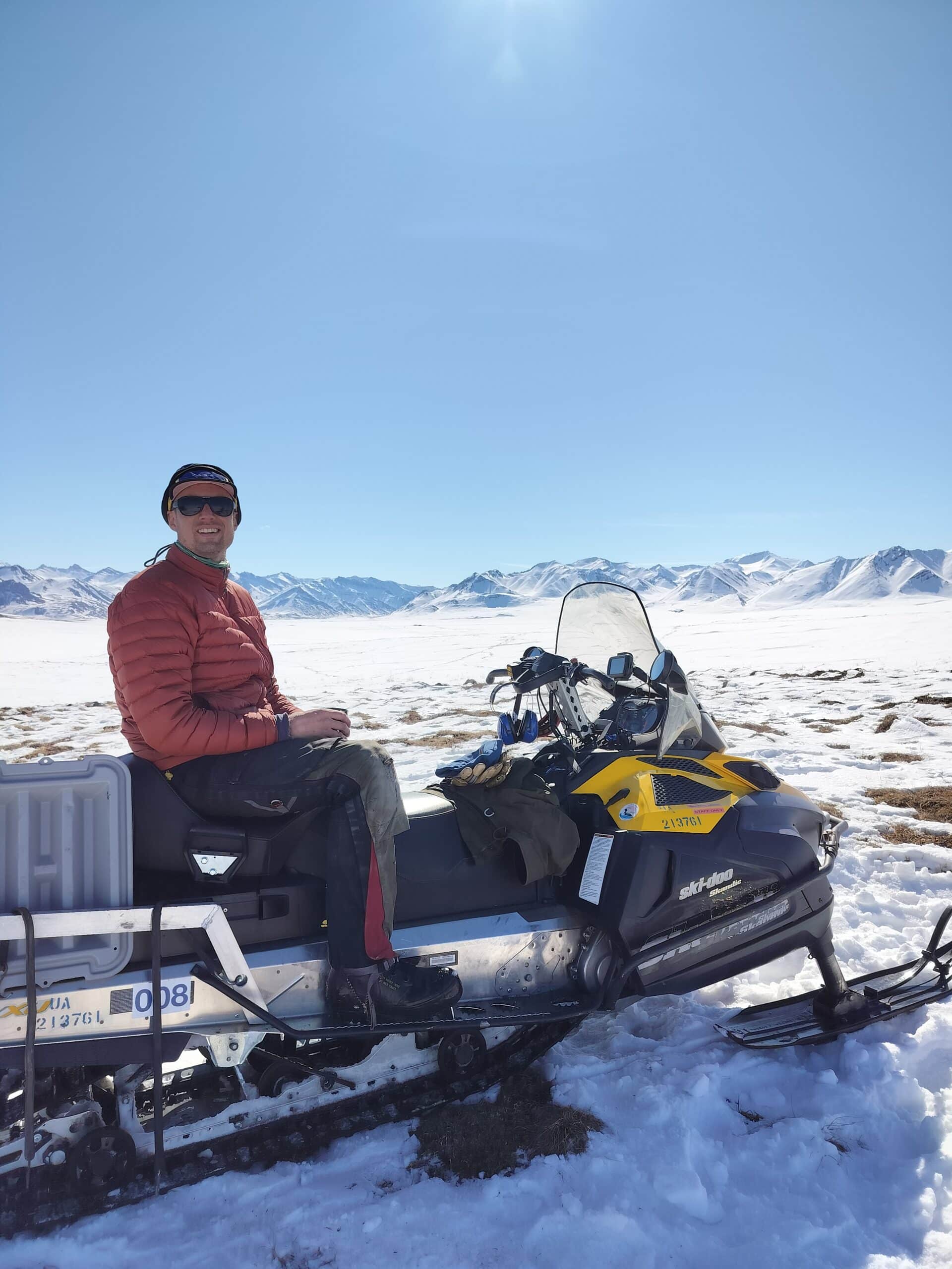 Kaj Lynoe sits on a snowmobile in the snowy tundray