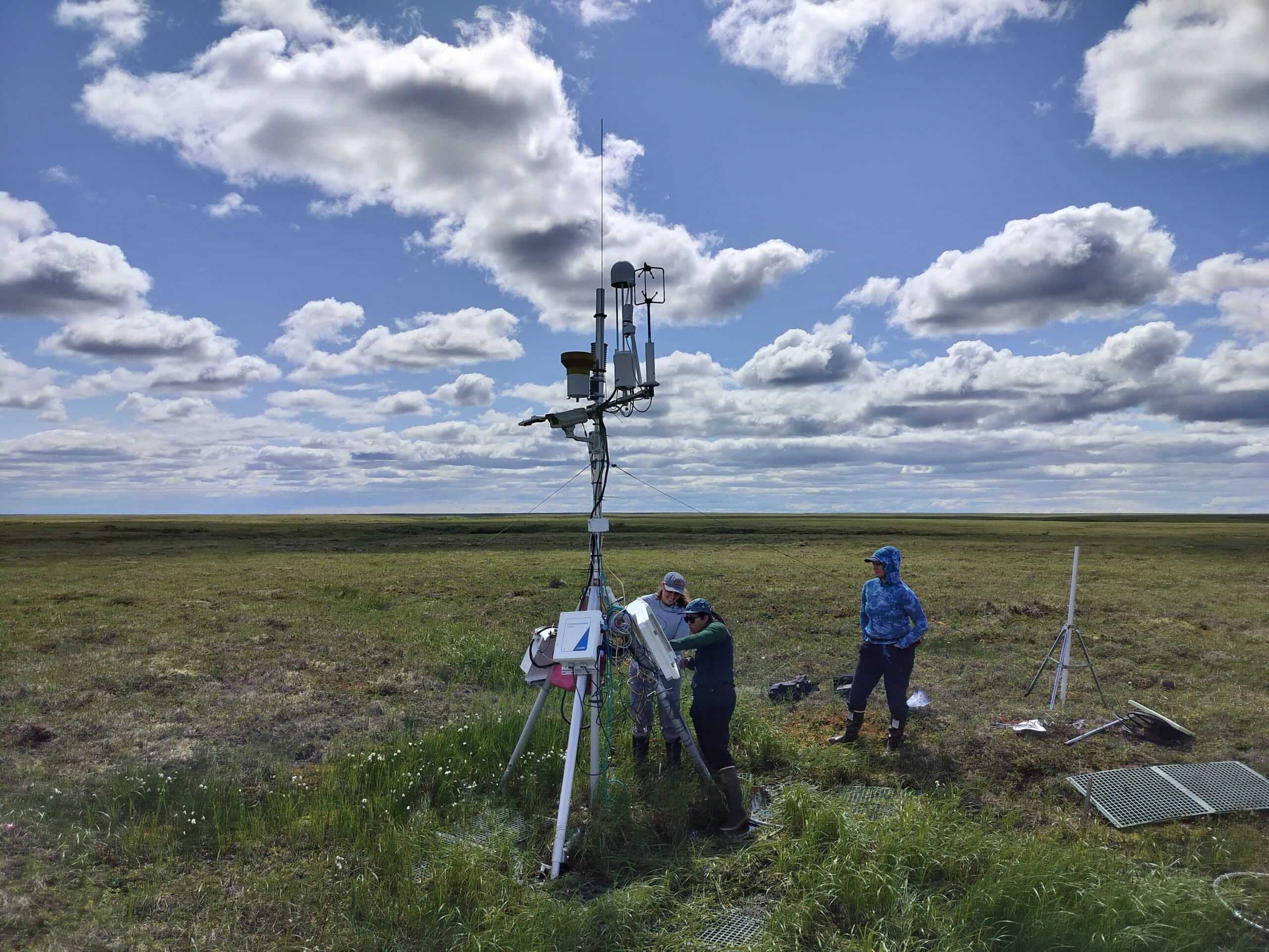 two women examine a carbon tower on the tundra of the YKD