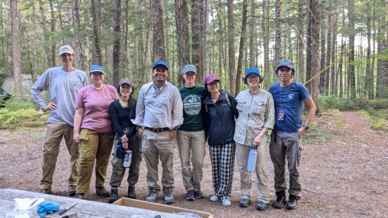 a group of people standing in the forest posing for a photo, smiling