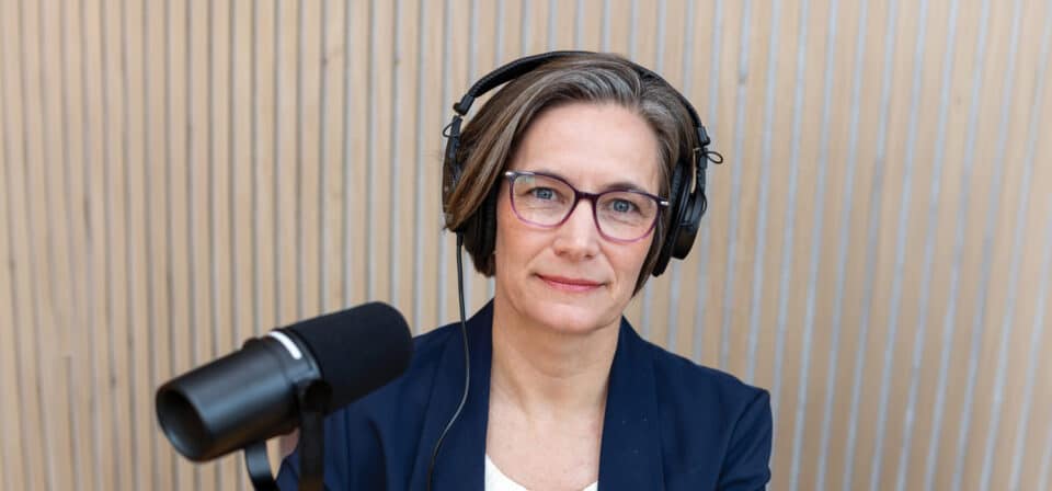headshot of Heather Goldstone with headphones and a microphone