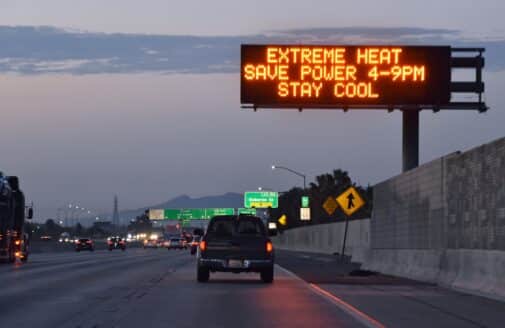 a car driving on a highway under a sign warning of extreme heat