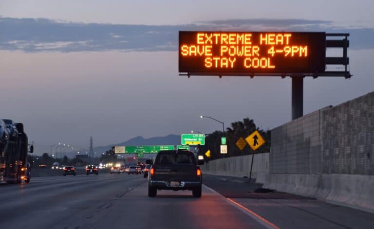 a car driving on a highway under a sign warning of extreme heat