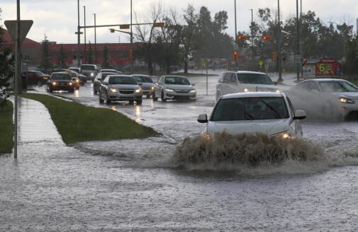 cars driving through deep puddles on a suburban street