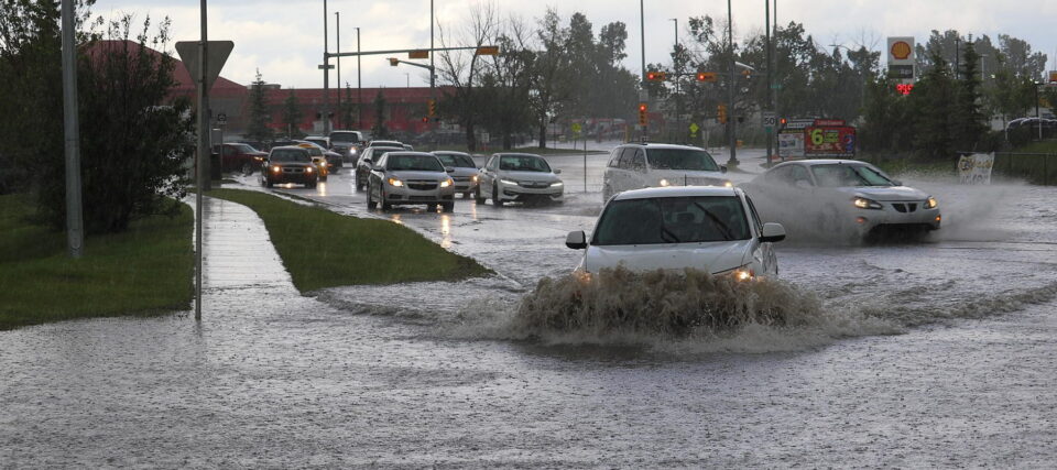 cars driving through deep puddles on a suburban street