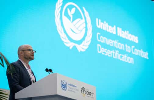 a man stands at a podium in front of a screen that reads "united nations convention to combat desertification"