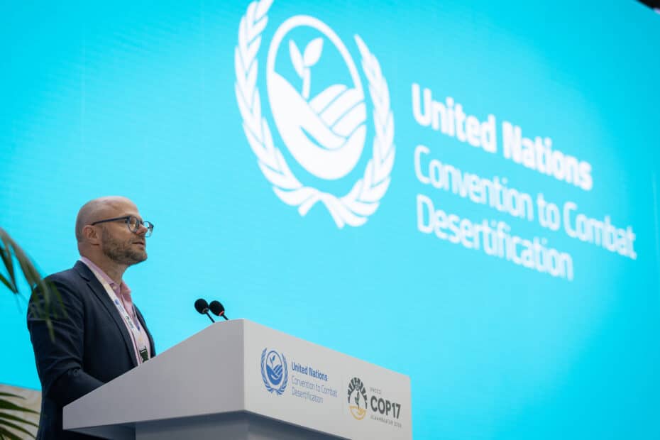 a man stands at a podium in front of a screen that reads 